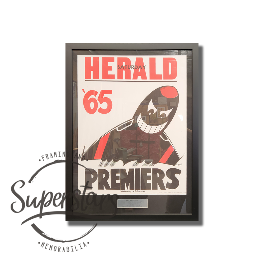 Essendon Premiership Memorabilia. 1965 VFL Premiers. A cartoon bomber is the main feature, with the word Premiers across the bottom. This has been framed with a black border, black timber frame and silver plaque.