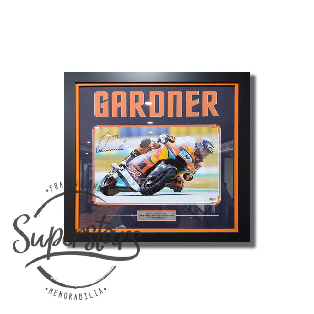 Remy Gardner memorabilia. A photo of Remy Gardner on his motorbike during a race. The photo is framed with a black border, and orange wording that spells our Gardner. There is a orange and black frame around the photo and word art