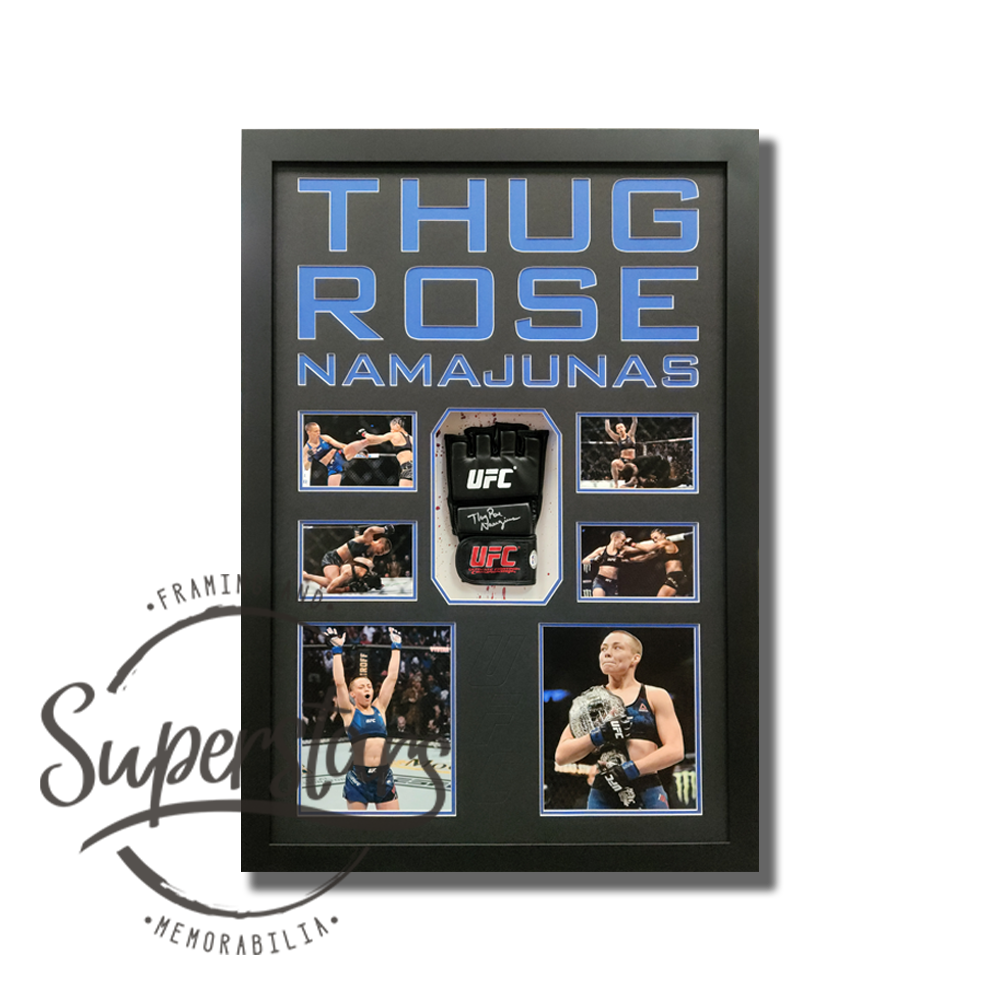Rose Namajunas signed UFC glove is surrounded by action photos with the words Thug Rose Namajunas across the top. It has a black timber frame, blue wording, black borders and blue trim line. UFC has been embossed between the two larger photos.