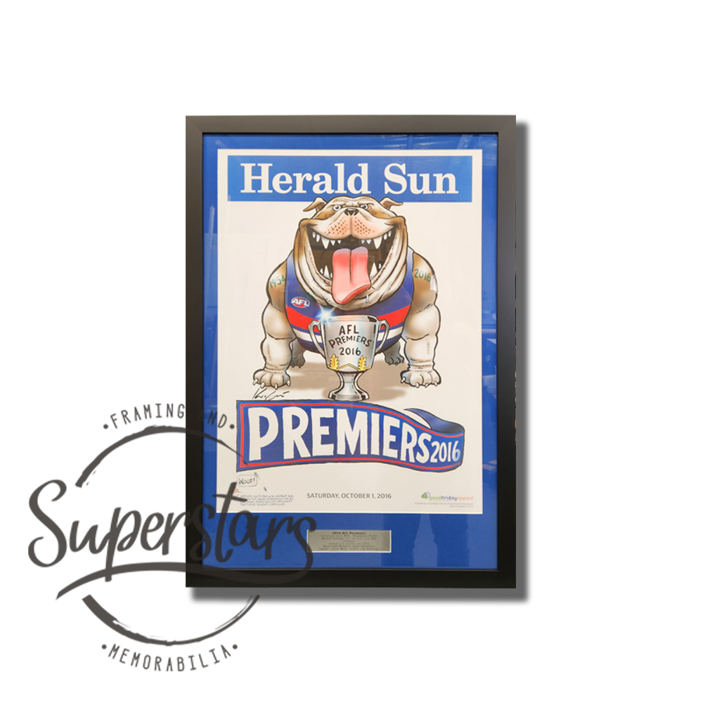Western Bulldogs Premiership Memorabilia. 2021 AFL Premiers. A cartoon bulldog is the main feature, with the word Premiers 2016 across the bottom. This has been framed with a blue border, black timber frame and plaque.